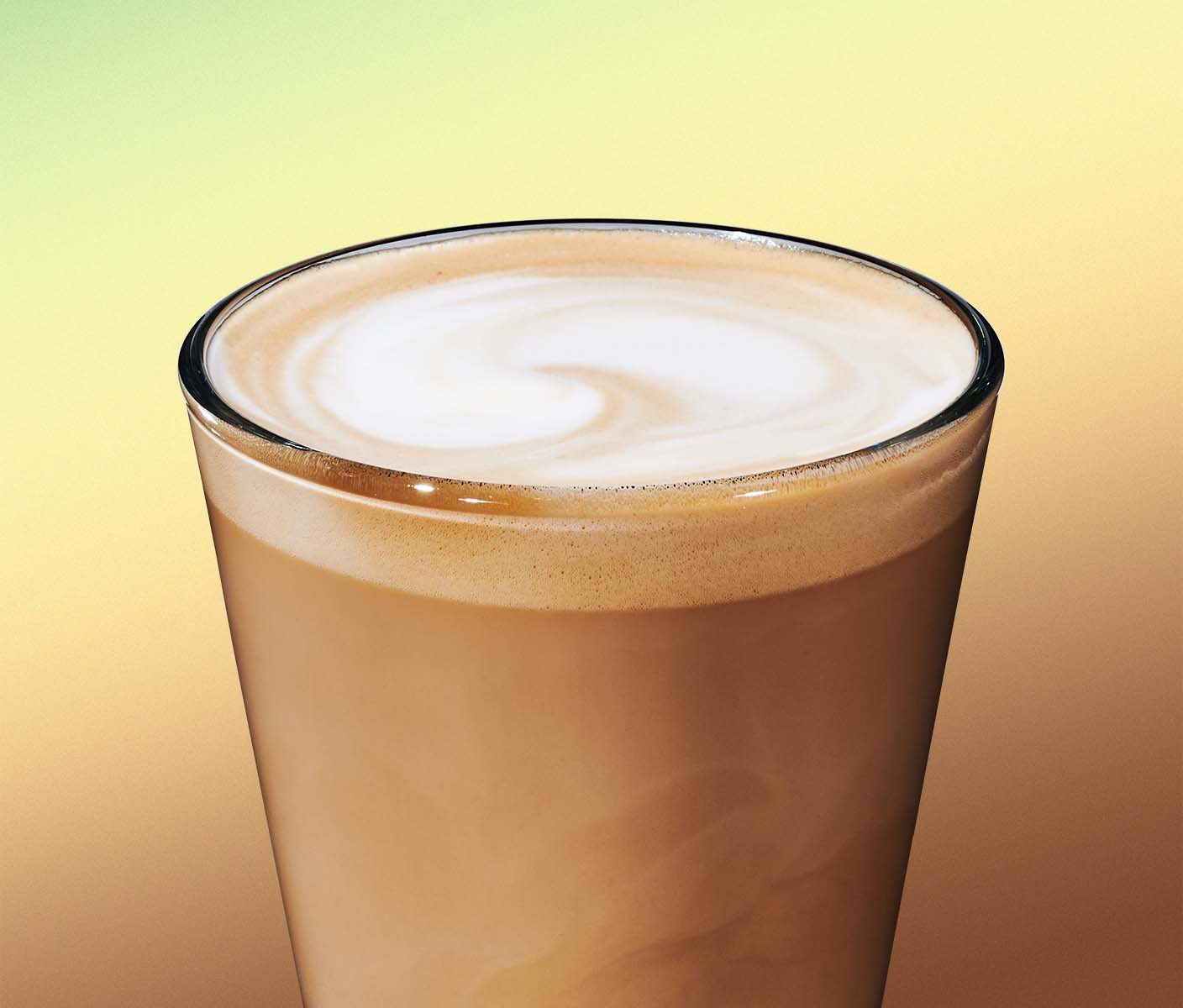 A espresso based beverage in glassware with a frothed top on a green background.