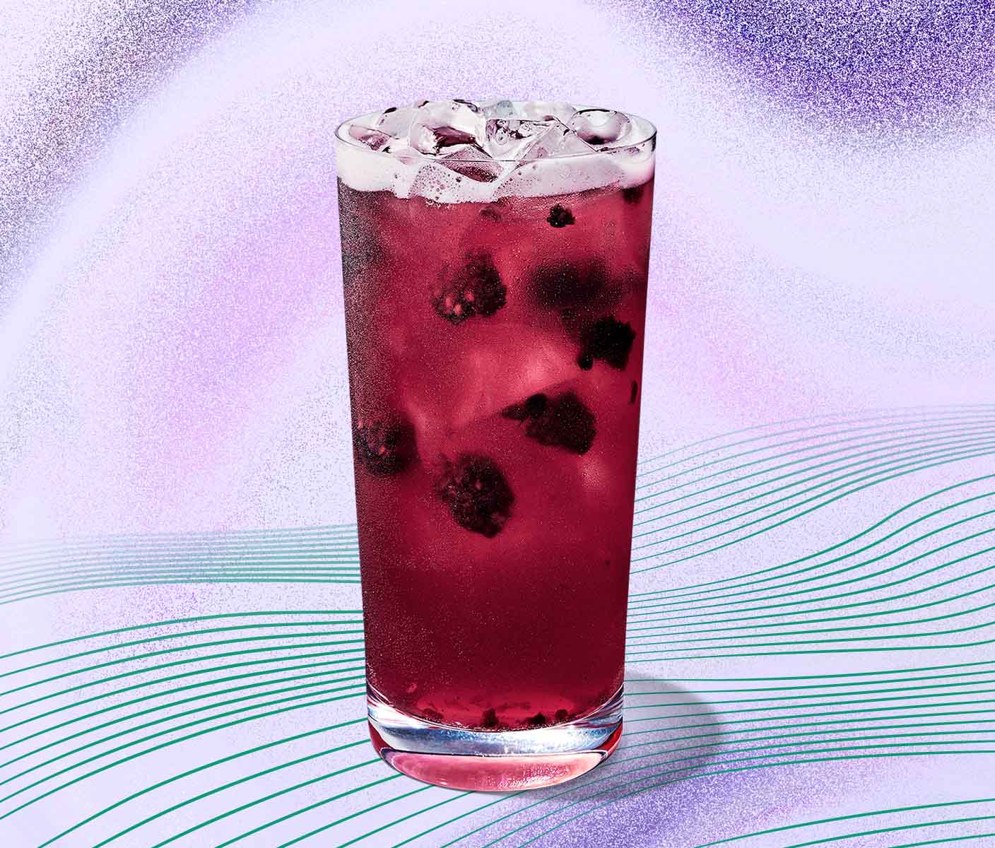 A Starbucks Refresher beverage in glassware that is a translucent purple colour with blackberry inclusions and ice visible,  on a pale purple background with radiating green lines.