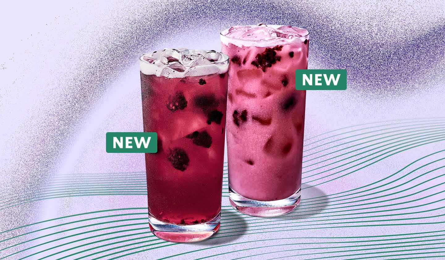 Two Starbucks Refresher beverages in glassware on a pale purple background with radiating green lines. One of drinks is a translucent purple colour with blackberry inclusions and ice visible and the second is lighter purple and more opaque. Each beverage has a small green sticker indicating it is new.