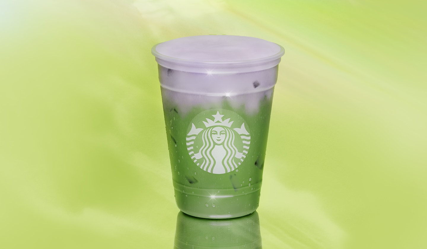 A green iced beverage topped with a light purple cold foam on a green background.