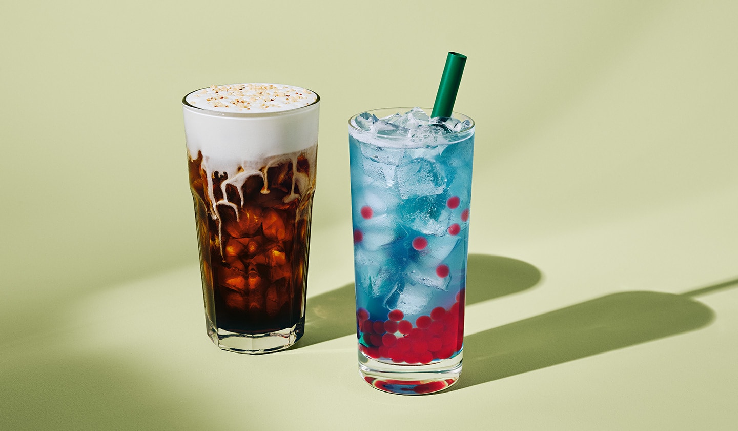 A refreshing cold brew topped with creamy cold foam and cookie crumbles, next to a vibrant blue lemonade with Raspberry Flavoured Pearls.