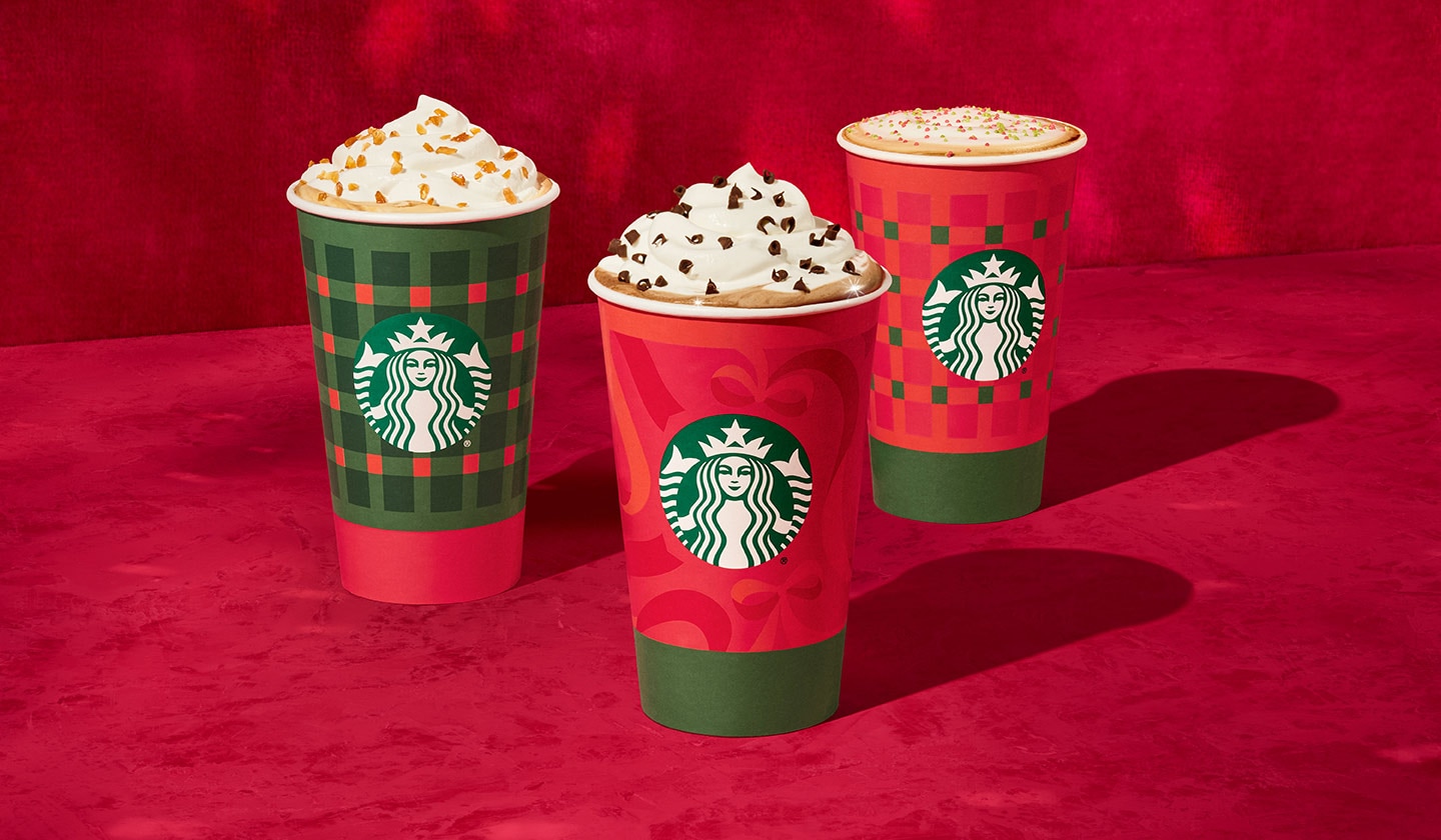 Trois tasses des Fêtes remplies à ras bord de garnitures délicieuses et originales, sur un fond rouge vif où se reflètent des lumières scintillantes.