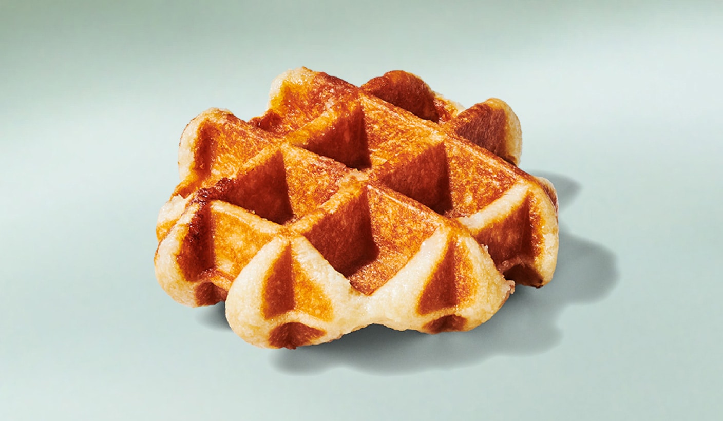 Une appétissante gaufre dorée recouverte de cristaux de sucre, sur un fond vert menthe.