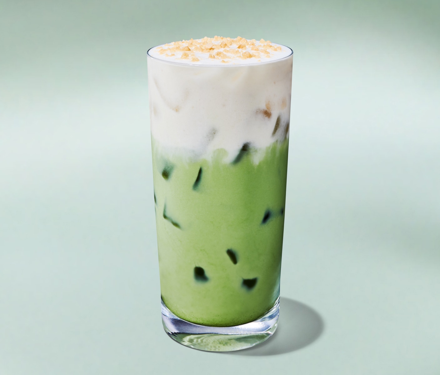 Un matcha latte glacé rafraîchissant dans un grand verre, sur un fond vert menthe.