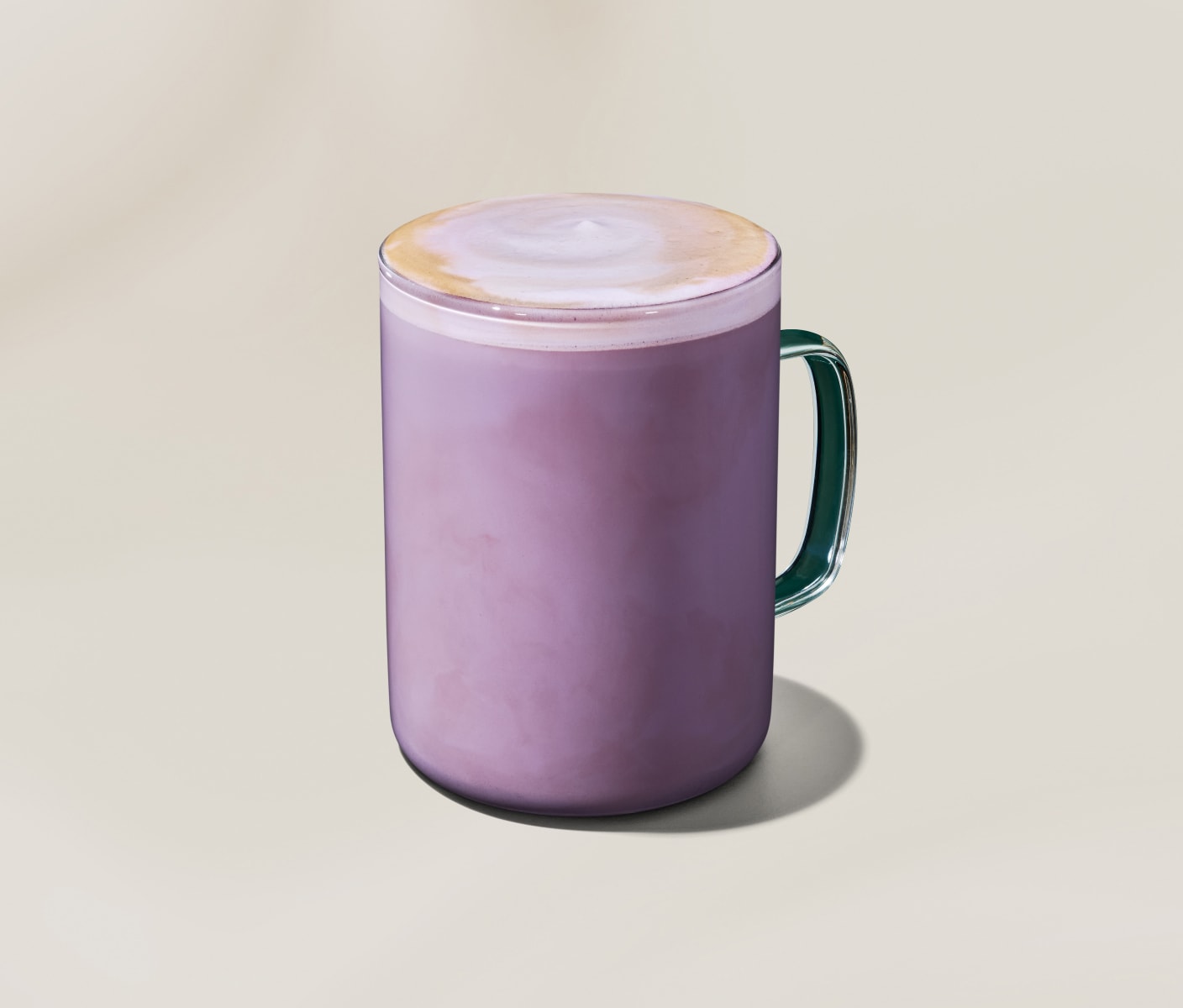 Un latte chaud de couleur lavande dans une tasse en verre, avec un tourbillon d'espresso et de lait sur le dessus.