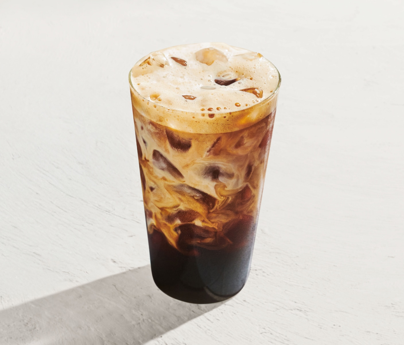 Un espresso glacé marbré, présenté sur un fond blanc lumineux.