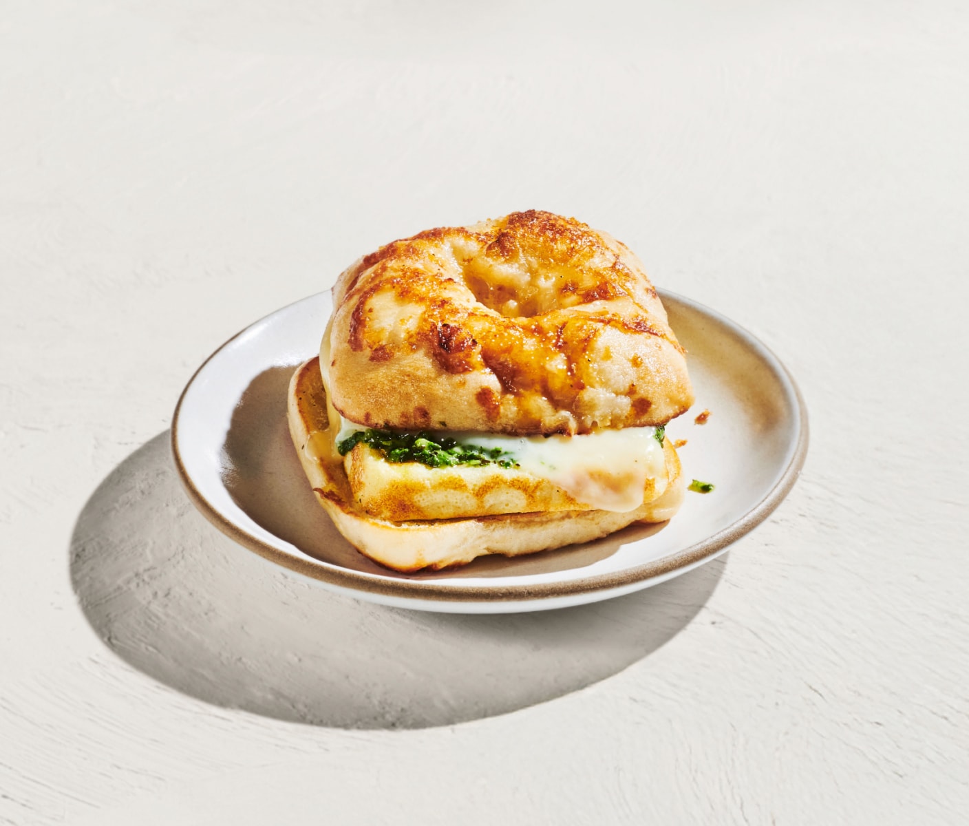 Un sandwich déjeuner au fromage présenté sur un fond blanc lumineux.
