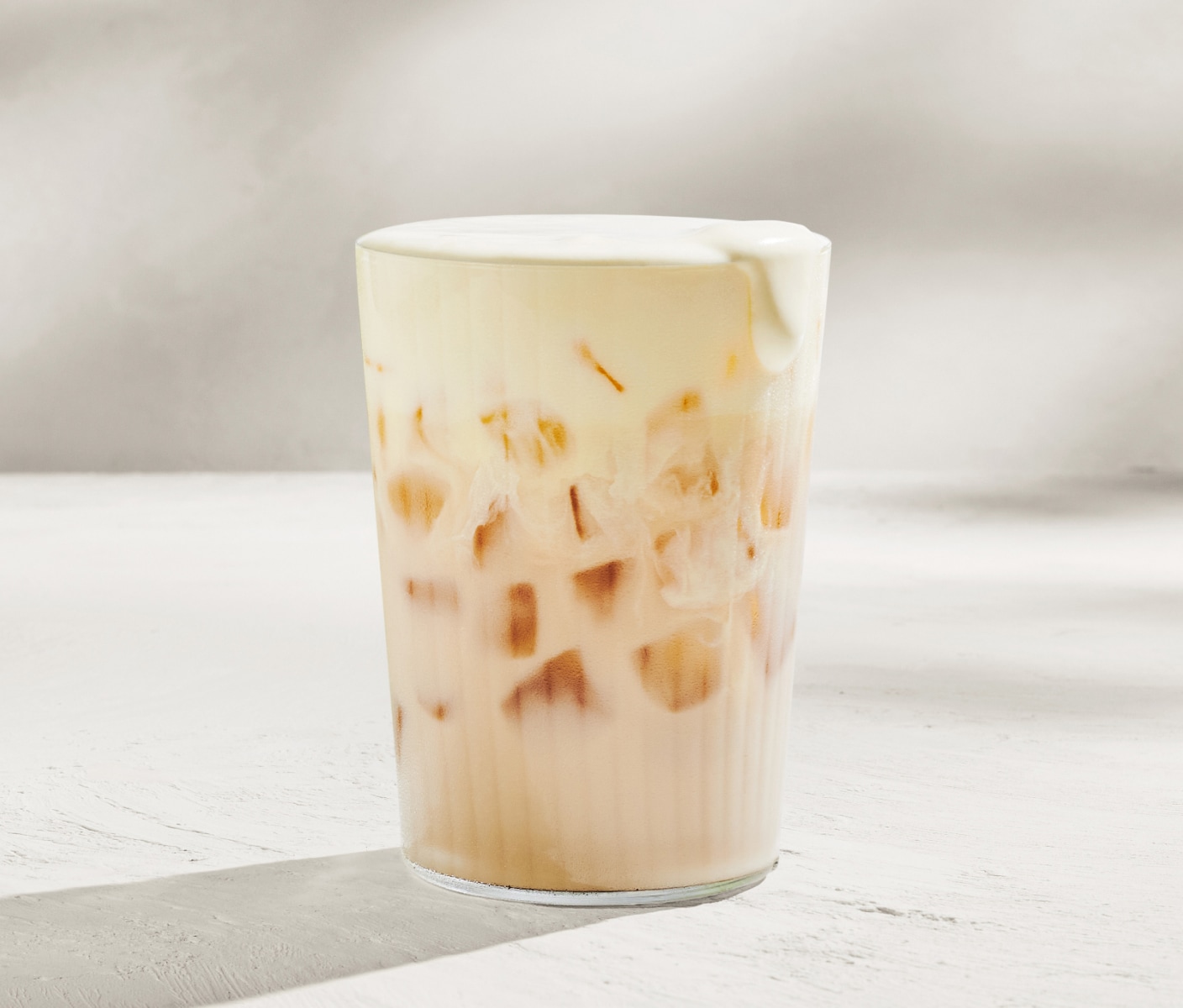 Un chai glacé garni d’une mousse froide crémeuse à la mangue de couleur jaune.