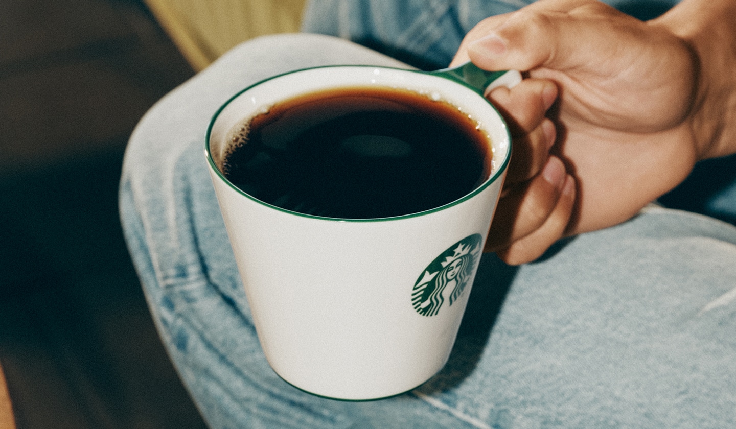 Plan rapproché d’une personne qui tient une tasse de café.
