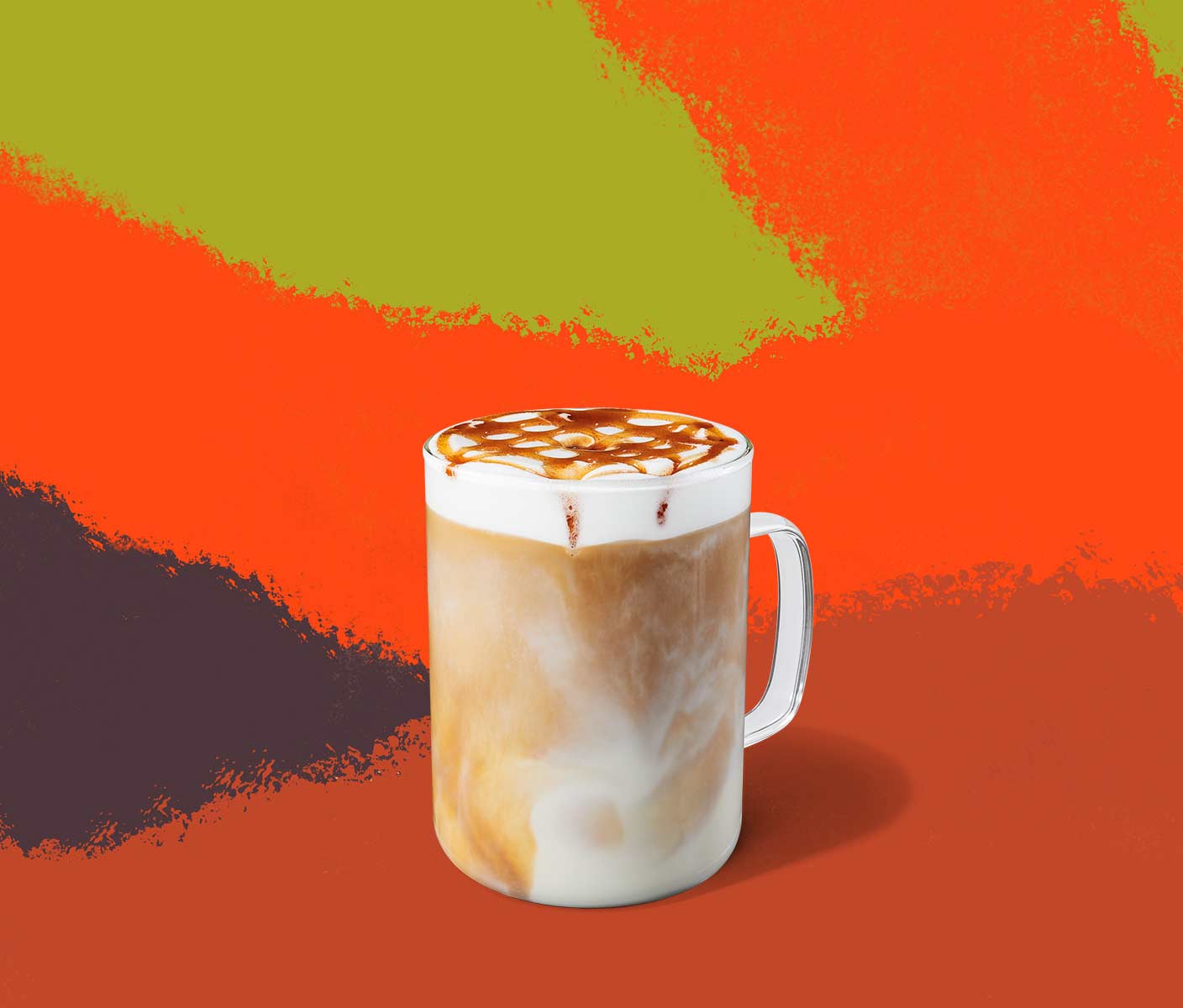 Une boisson chaude et crémeuse à base de café garnie de mousse et d’un coulis formant un quadrillage, servie dans une tasse en verre.