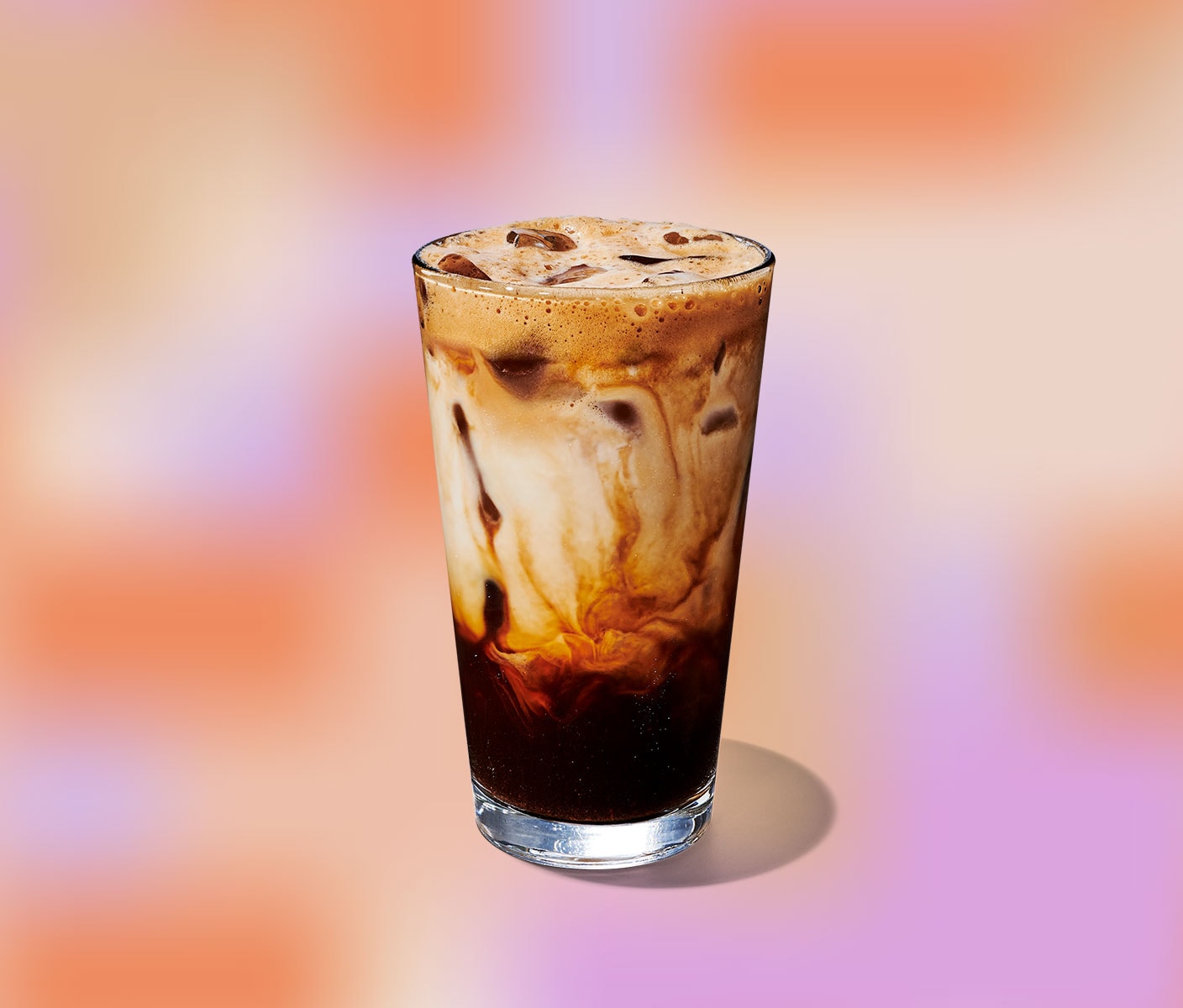 Un grand verre transparent contenant de l’espresso foncé dans le bas et un tourbillon crémeux dans le haut.