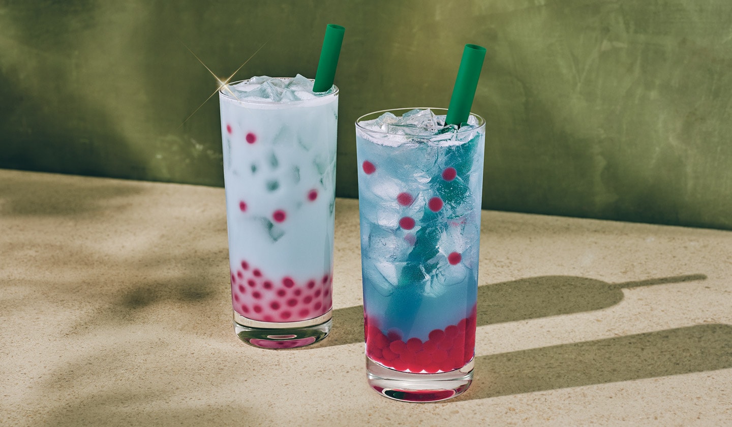 Une boisson rafraîchissante à la noix de coco bleu laiteux, à côté d’une limonade bleu vif, toutes deux garnies de perles aromatisées à la framboise.